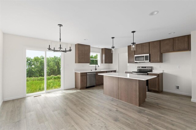 102 Harrow Dr, Ofallon, MO 63385 - kitchen with stainless steel appliances, light wood-type flooring, baseboards, light countertops, and a chandelier
