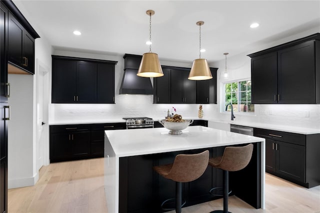 2017 Woodsey Dr, Brentwood, MO 63144 - kitchen featuring premium range hood, dark cabinets, backsplash, light wood-style flooring, and a kitchen island