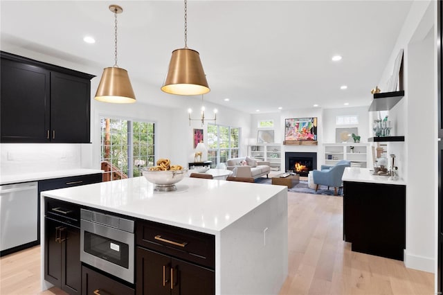 2017 Woodsey Dr, Brentwood, MO 63144 - kitchen featuring stainless steel appliances, light wood-style flooring, light countertops, a warm lit fireplace, and recessed lighting