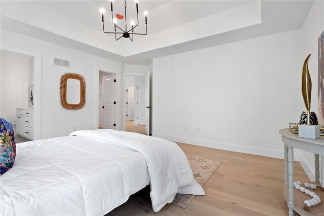2017 Woodsey Dr, Brentwood, MO 63144 - bedroom featuring a chandelier, a tray ceiling, light wood finished floors, and baseboards
