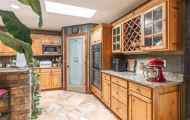 10010 Edmondson Hills Dr, Rolla, MO 65401 - kitchen with stainless steel microwave, multiple ovens, a skylight, tasteful backsplash, and light stone countertops
