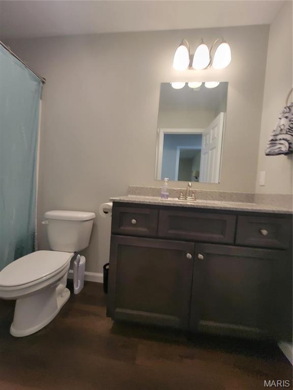 301 S Sloan St, Lebanon, MO 65536 - bathroom featuring toilet, wood finished floors, vanity, curtained shower, and baseboards