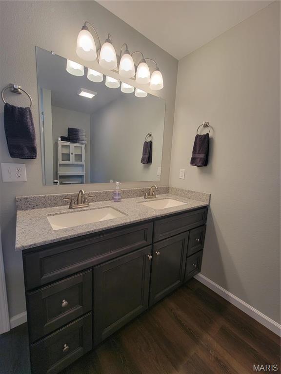 301 S Sloan St, Lebanon, MO 65536 - bathroom featuring wood finished floors, double vanity, and baseboards