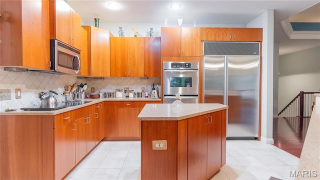kitchen with stainless steel appliances, a center island, light countertops, and tasteful backsplash