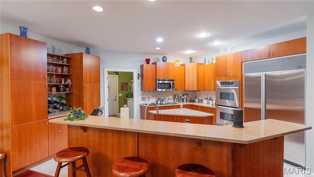 kitchen with stainless steel appliances, open shelves, a kitchen island, tasteful backsplash, and a kitchen breakfast bar