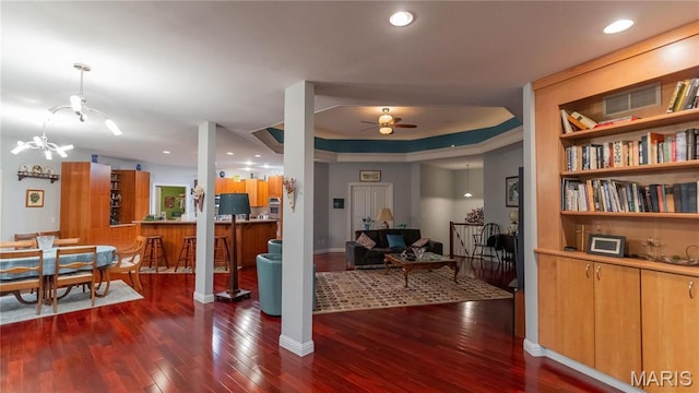 living room featuring ceiling fan, wood finished floors, a raised ceiling, and baseboards