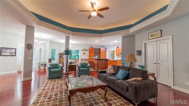 living area with a raised ceiling, hardwood / wood-style flooring, a ceiling fan, baseboards, and crown molding
