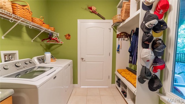 clothes washing area featuring washing machine and clothes dryer, light tile patterned flooring, and baseboards