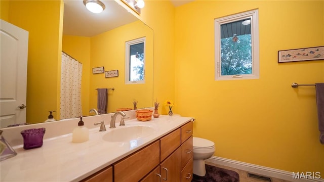 bathroom with toilet, vanity, healthy amount of natural light, and baseboards