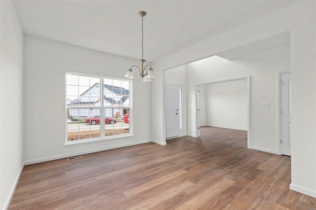 unfurnished dining area featuring a chandelier, light wood-style flooring, and baseboards