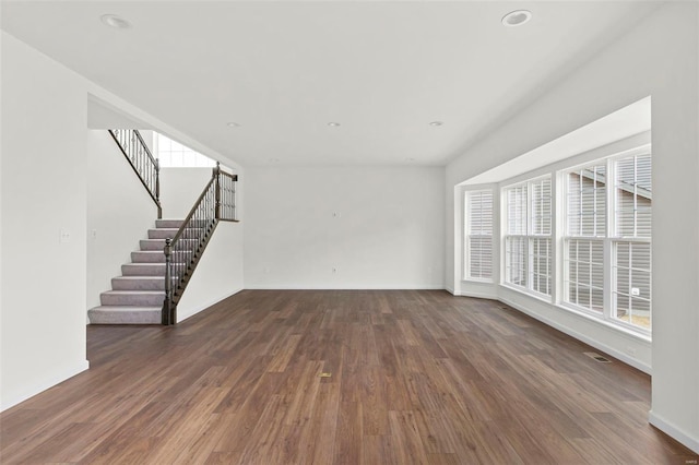 unfurnished living room with wood finished floors, stairway, baseboards, and recessed lighting