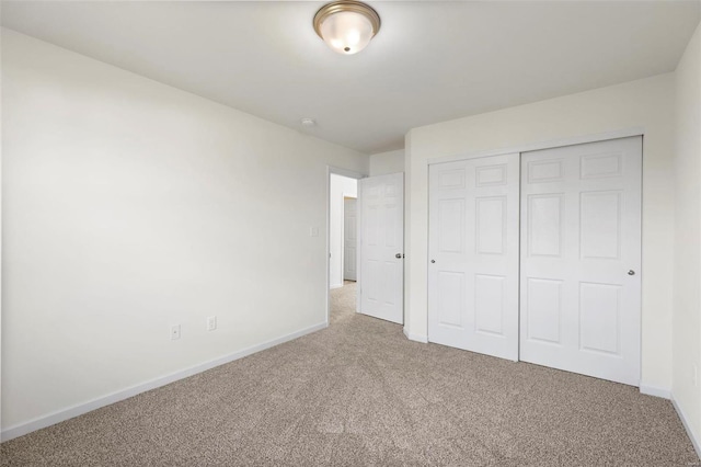 unfurnished bedroom with carpet flooring, baseboards, and a closet