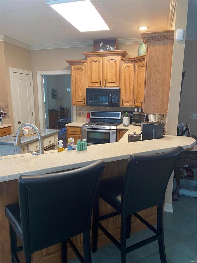 kitchen with stainless steel appliances, light countertops, a breakfast bar area, tasteful backsplash, and ornamental molding