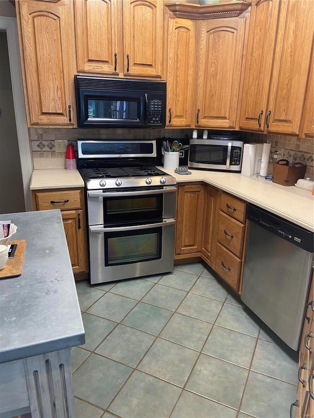 kitchen with stainless steel appliances, tasteful backsplash, light tile patterned flooring, and light countertops