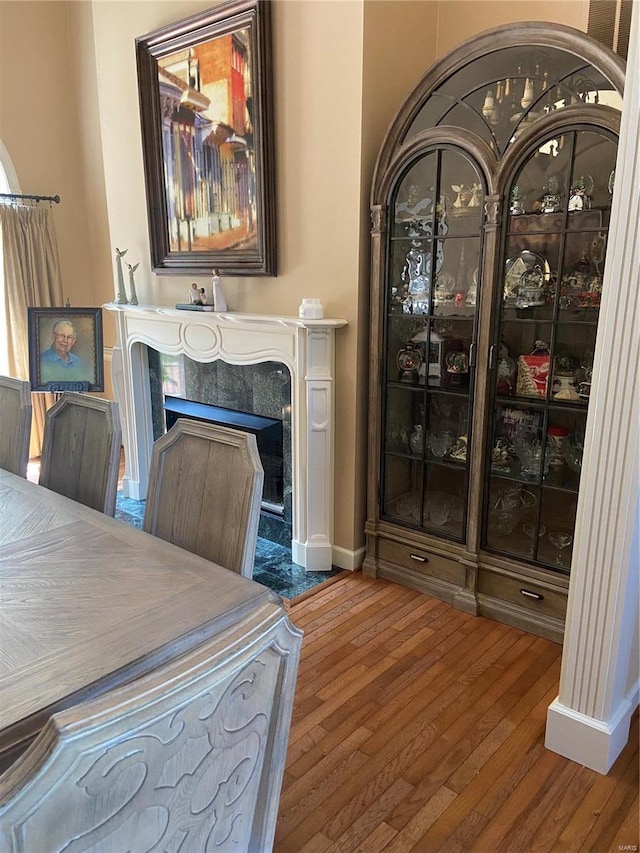 dining space with a premium fireplace, hardwood / wood-style flooring, and baseboards