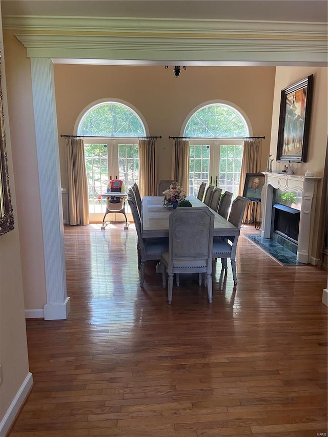 dining room with hardwood / wood-style floors, a fireplace, plenty of natural light, baseboards, and crown molding