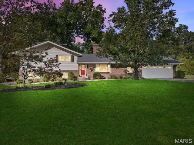 split level home with a yard, brick siding, driveway, a chimney, and an attached garage