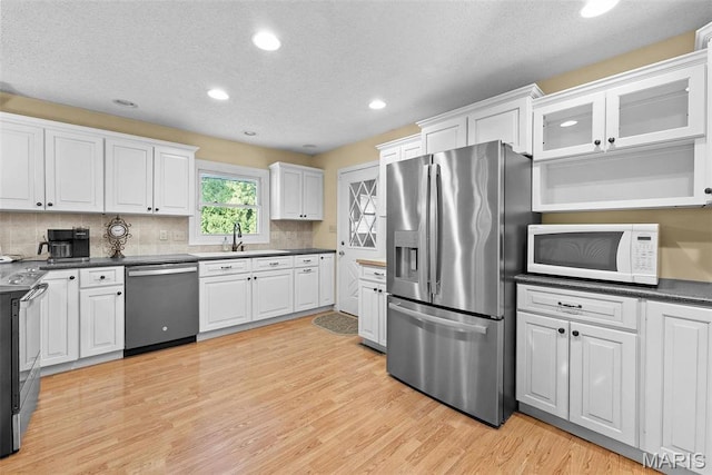 kitchen featuring appliances with stainless steel finishes, white cabinetry, recessed lighting, light wood-style flooring, and tasteful backsplash