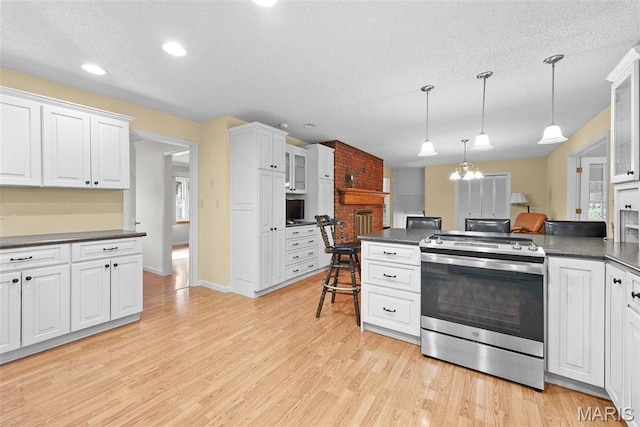 kitchen with electric stove, dark countertops, white cabinets, glass insert cabinets, and light wood-style flooring