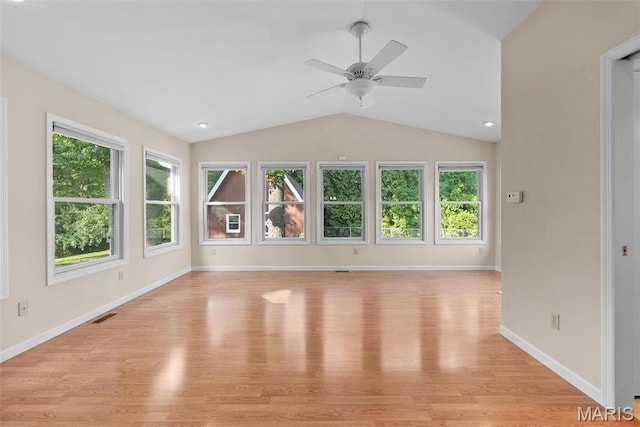 unfurnished living room featuring healthy amount of natural light, vaulted ceiling, a ceiling fan, light wood finished floors, and baseboards