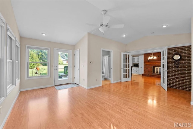 unfurnished living room featuring lofted ceiling, light wood-style floors, baseboards, and a ceiling fan