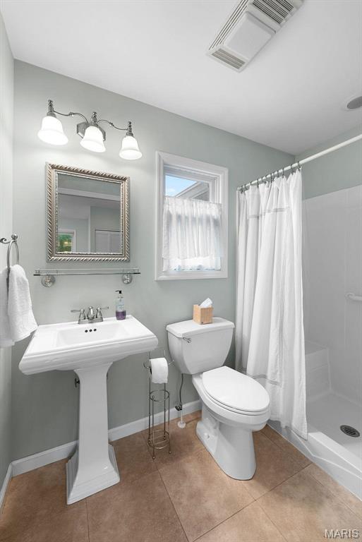 bathroom with toilet, curtained shower, tile patterned floors, and baseboards