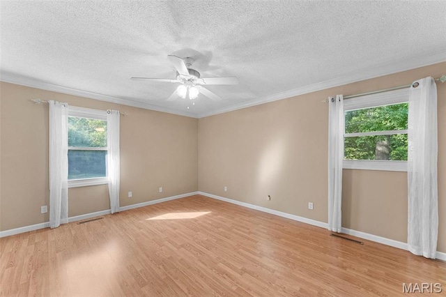 empty room featuring light wood-type flooring, a ceiling fan, ornamental molding, a textured ceiling, and baseboards
