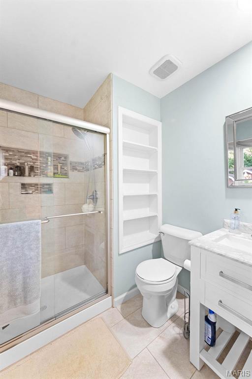 bathroom featuring a stall shower, toilet, tile patterned flooring, and vanity
