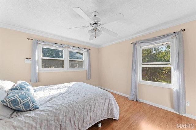 bedroom with wood finished floors, crown molding, baseboards, a textured ceiling, and ceiling fan