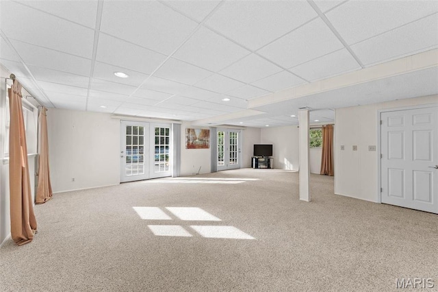 below grade area featuring carpet flooring, a paneled ceiling, recessed lighting, french doors, and baseboards