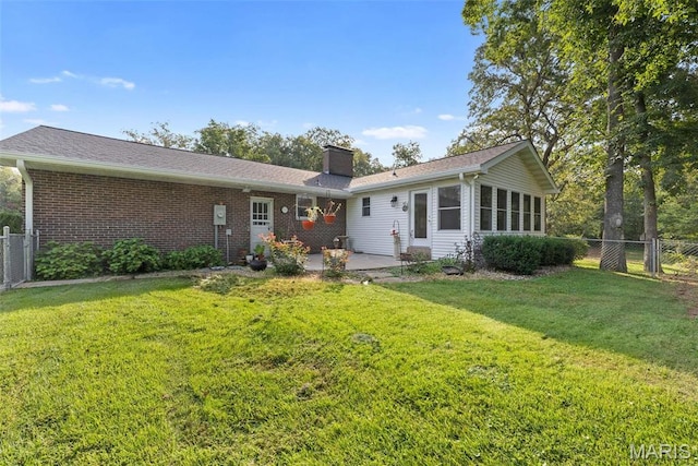 rear view of house featuring a patio, a chimney, brick siding, and a gate