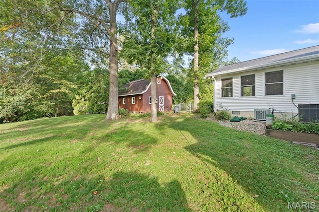 view of grassy yard with central AC unit, an outdoor structure, and a shed