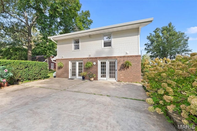 rear view of property with brick siding, french doors, and a patio