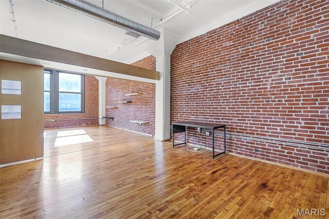1010 Saint Charles St Unit 803, Saint Louis, MO 63101 - unfurnished living room with brick wall, hardwood / wood-style floors, and a high ceiling