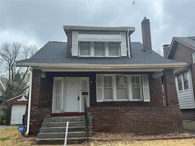 7210 Normandy Pl, Saint Louis, MO 63121 - bungalow-style home featuring brick siding, a chimney, entry steps, covered porch, and an outbuilding