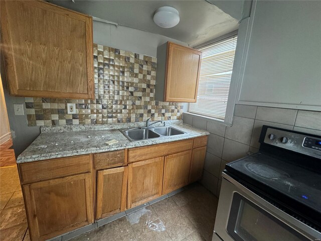 7210 Normandy Pl, Saint Louis, MO 63121 - kitchen featuring electric range, a sink, tasteful backsplash, light stone counters, and brown cabinetry
