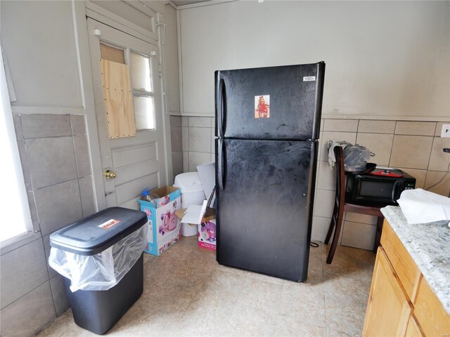 7210 Normandy Pl, Saint Louis, MO 63121 - kitchen with freestanding refrigerator, tile walls, a wainscoted wall, and light countertops