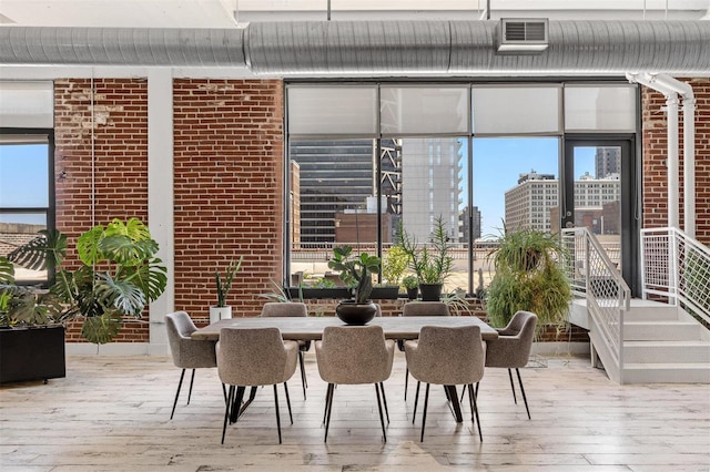dining space featuring hardwood / wood-style flooring and brick wall