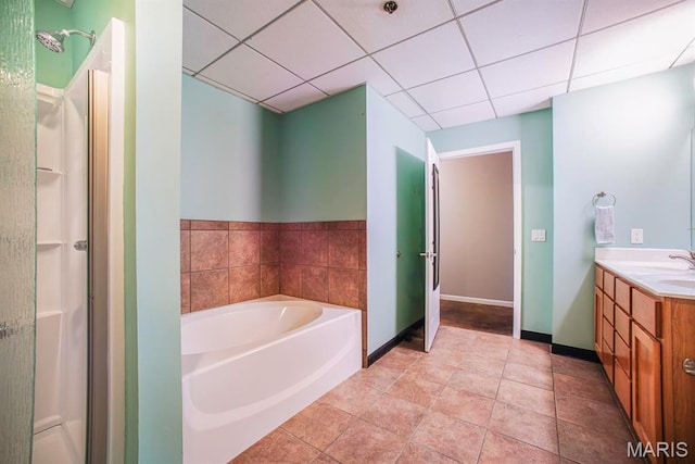 full bath featuring vanity, a garden tub, a shower stall, baseboards, and a paneled ceiling