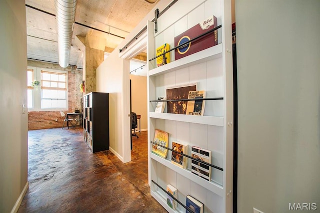 hall with concrete flooring and brick wall