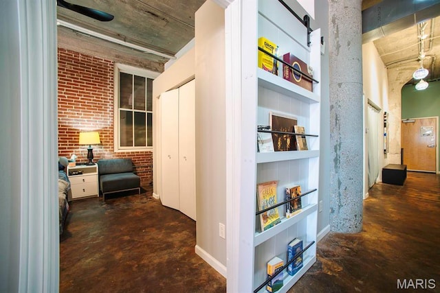 hallway with unfinished concrete flooring and brick wall