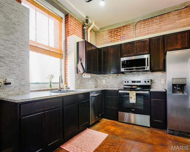 kitchen with appliances with stainless steel finishes, a sink, tasteful backsplash, and light stone countertops