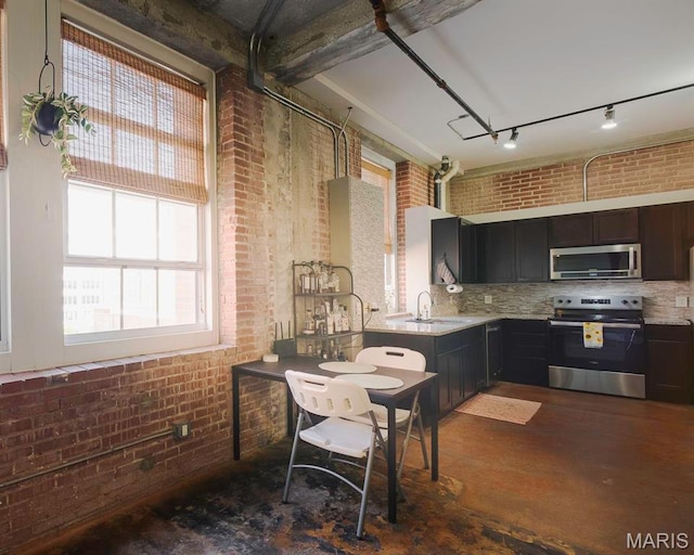 kitchen with appliances with stainless steel finishes, brick wall, backsplash, dark wood finished floors, and a sink
