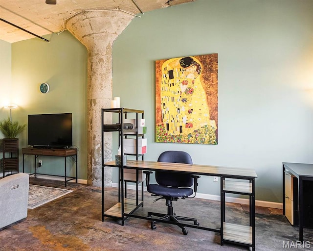 home office featuring concrete flooring and baseboards