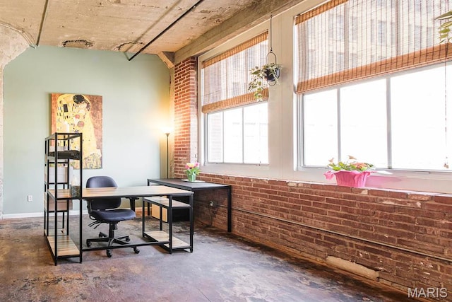 home office featuring brick wall and unfinished concrete floors