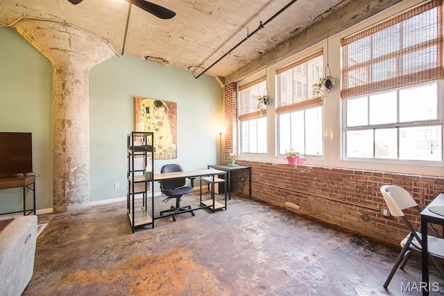 office area featuring brick wall, ceiling fan, and concrete flooring