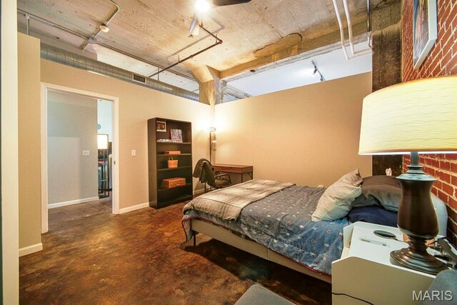 bedroom featuring concrete flooring and baseboards
