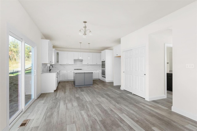 2438 Chukka Dr, Eureka, MO 63025 - kitchen with light wood finished floors, a chandelier, a center island, and a sink