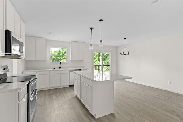 305 Winding Bluffs Ct, Fenton, MO 63026 - kitchen with appliances with stainless steel finishes, a sink, light wood-style floors, a center island, and light countertops