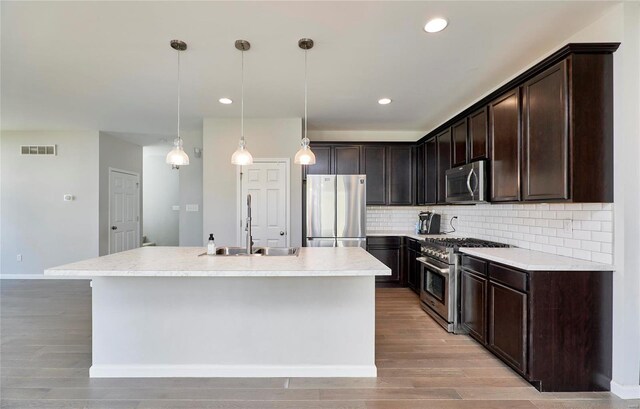 120 Kelcross, Wentzville, MO 63385 - kitchen with stainless steel appliances, a sink, a kitchen island with sink, dark brown cabinets, and light wood finished floors